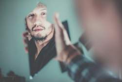 Man looking in broken mirror