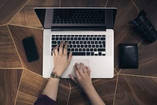 Photograph of a person using a laptop to lodge an expense claim on a wooden desk, by Fabian Irsara on Unsplash