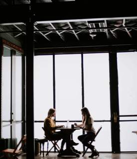 two people sitting at a table chatting