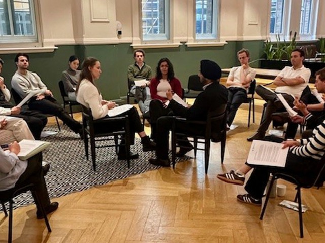 group of young people sitting in a circle of chairs